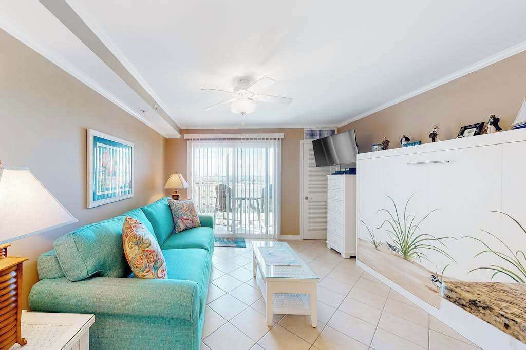 A living room with a teal sofa, a coffee table, a TV, and a cabinet.