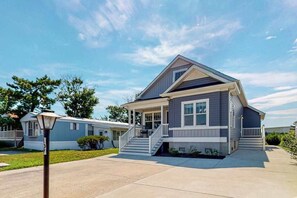 A single-story house with a front porch, a staircase leading to the entrance, and a clear sky. - New home steps from Northside Park with shared pools, tennis & pickleball (Ocean City)
