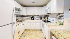 A modern kitchen with white cabinets, a microwave, a stove, and a coffee maker. - Ground-floor condo with pool & fenced patio - 4 blocks to the beach (Ocean City)