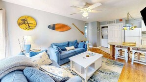A living room with a sofa, coffee table, and a ceiling fan. - Ground-floor condo with pool & fenced patio - 4 blocks to the beach (Ocean City)