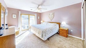 A bedroom with a bed, bedside tables, a ceiling fan, and a view through a sliding glass door. - Ground-floor condo with pool & fenced patio - 4 blocks to the beach (Ocean City)