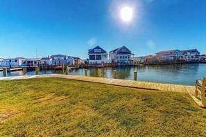 A waterfront property with a wooden dock, houses with large windows, and a clear sky. - Bayspot A-101 (Ocean City)