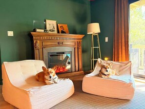 A cozy room with a fireplace, two armchairs, and a dog bed.