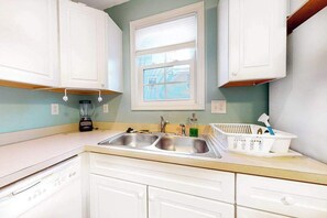 A kitchen with white cabinets, a double sink, a window, and a blender on the counter. - Large duplex w/2 separate homes, two kitchens, patio, WiFi, & great location (Ocean City)