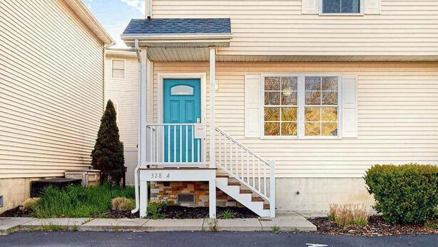 Une maison à deux étages avec une porte bleue, des balustrades blanches et un petit porche.