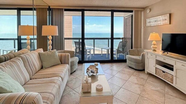 Une chambre d’hôtel dotée d’un grand balcon, d’un canapé, d’une télévision et d’une table basse.
