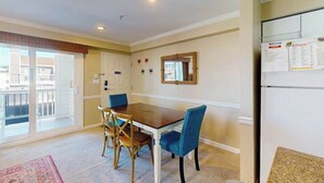 A dining area with a table and chairs, a refrigerator, a mirror, and a view of the outside.