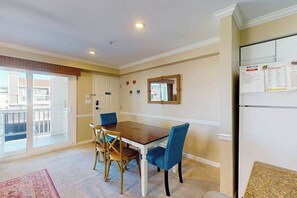 A dining area with a table and chairs, a refrigerator, a mirror, and a view of the outside. - Sunny condo w/balconies, full kitchen, A/C & Wifi & just steps to the beach (Ocean City)