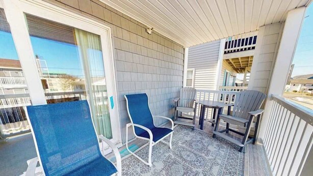 A balcony with a patterned floor, a table, and two chairs.