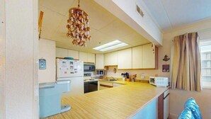 A compact kitchen with a central island, a microwave, a refrigerator, and a sink. - Excalibur 107 (Ocean City)