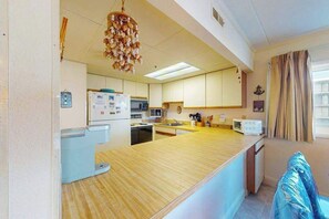 Una cocina compacta con una isla central, microondas, refrigerador y pileta.
