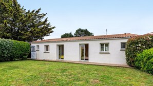 A single-story building with a tiled roof, a small front yard, and a white exterior.