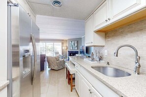 Eine moderne Küche mit einem Edelstahlkühlschrank, einer Granitarbeitsplatte und einem Spülbecken.