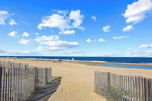 Ein Strand mit einer Holzzahlung, einem Rettungsturm und dem Meer im Hintergrund.
