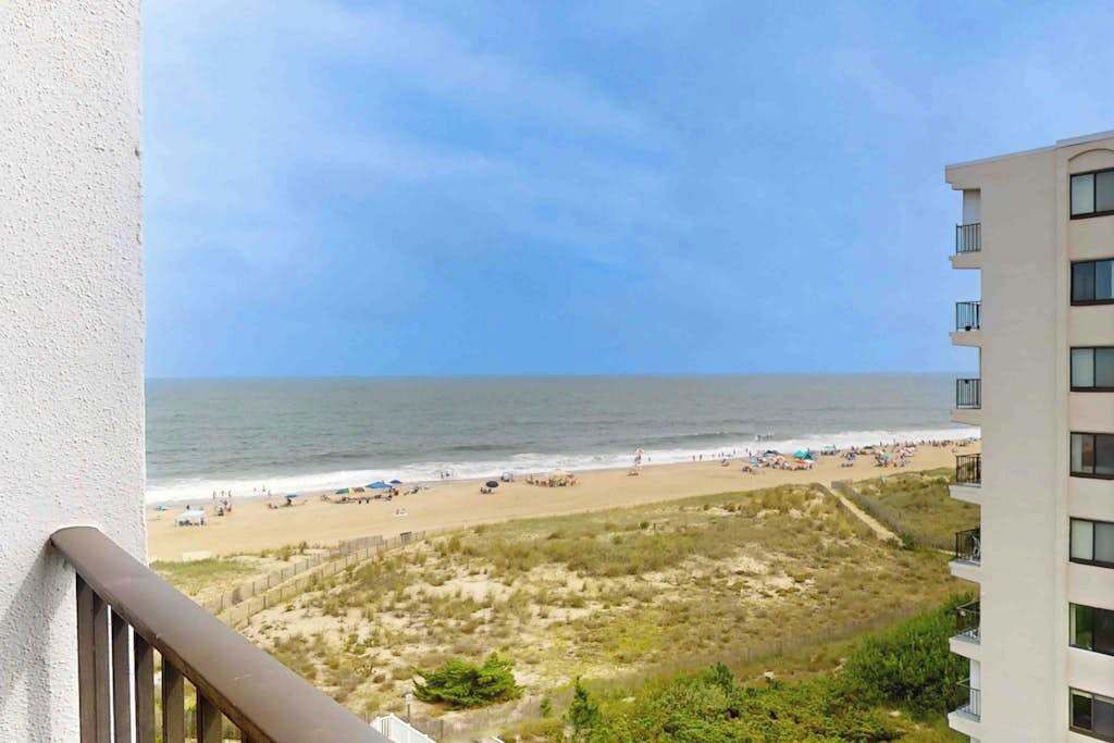 Vista de una playa desde un balcón con un edificio a la derecha.