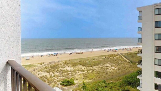 A view of a beach from a balcony with a building on the right. - Camelot 603B (Ocean City)