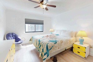 A bedroom with a bed, a chair, a nightstand, a lamp, a ceiling fan, and a window. - Luxury Ocean View Condo w/Shared Olympic Pool, Tennis, balcony & WiFi (Ocean City)