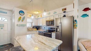 A kitchen with a marble island, stainless steel appliances, pendant lights, and decorative fish decals. - Sunny canal side condo - w/balcony, short walk to the beach, boardwalk, & parks (Ocean City)