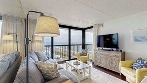 En moderne stue med sofa, lænestol, sofabord og fjernsyn.