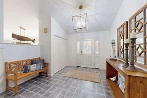 A hallway with a wooden bench, a rug, a chandelier, and a door with stained glass. - Salty Way (Ocean Pines)