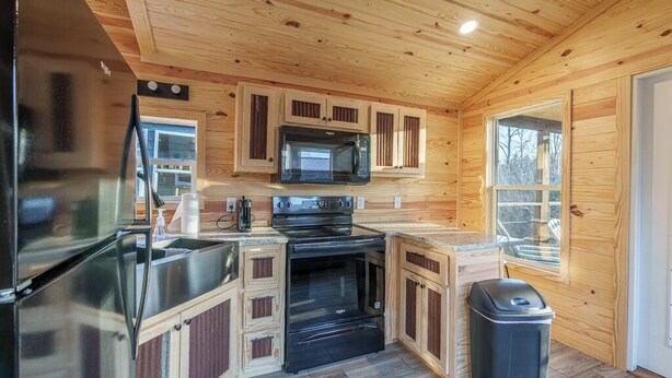 A compact kitchen with wooden cabinets, a stainless steel refrigerator, a microwave, and an oven.