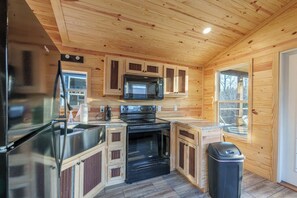 Una cucina compatta con mobili in legno, un frigorifero in acciaio inox, un forno a microonde e un forno.