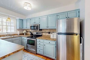 Eine moderne Küche mit hellblauen Schränken, Edelstahlgeräten und einem großen Kühlschrank.