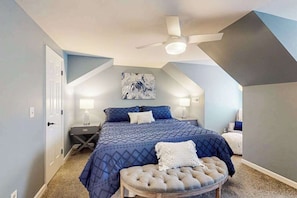 Ein Schlafzimmer mit Bett, Deckenventilator, Wandkunst und Nachttisch.