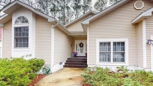 A two-story house with a front porch, a small garden, and a visible garage door. - 22 Harpoon Rd (Ocean Pines)