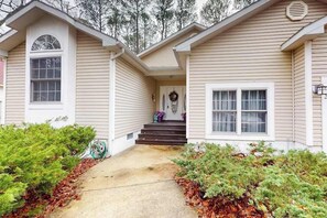 A two-story house with a front porch, a small garden, and a visible garage door. - 22 Harpoon Rd (Ocean Pines)
