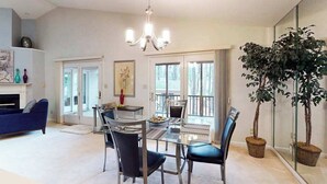 A spacious living area with a glass dining table, blue sofa, and a large potted plant. - 22 Harpoon Rd (Ocean Pines)