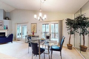 A spacious living area with a glass dining table, blue sofa, and a large potted plant. - 22 Harpoon Rd (Ocean Pines)