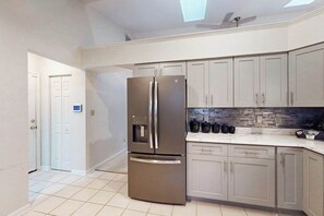 A modern kitchen with a stainless steel refrigerator, light grey cabinets, and a tiled floor. - 22 Harpoon Rd (Ocean Pines)