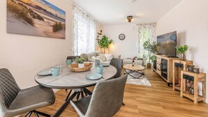 Ein modernes Wohnzimmer mit Essbereich, Fernseher und einem großen Gemälde an der Wand.