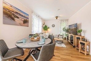 Ein modernes Wohnzimmer mit Essbereich, Fernseher und einem großen Gemälde an der Wand.