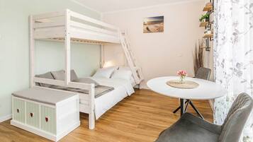 Ein Etagenbett mit Schreibtisch und Stuhl, ein kleiner Tisch mit einer Vase sowie ein an der Wand befestigtes Regal mit Pflanzen.