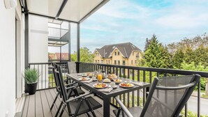 Ein Balkon mit Frühstückstisch, Stühlen und einem Blumentopf.