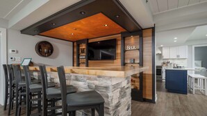 Eine Bar mit einer Steintheke, Holzbalkendecke und Barhocker.