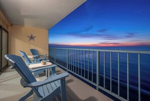 Ein Balkon mit zwei Adirondack-Stühlen, einem kleinen Tisch und einem dekorativen Stern an der Wand.