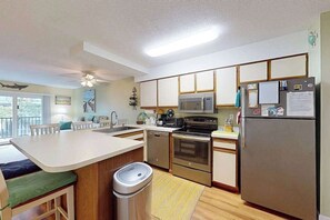 A modern kitchen with a central island, stainless steel appliances, and a refrigerator with magnets. - Sunny Ocean block condo with balcony, AC, WiFi & laundry - walk to the beach (Ocean City)