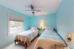 A bedroom with two beds, a ceiling fan, a window, and a nightstand with a lamp. - Sunny Ocean block condo with balcony, AC, WiFi & laundry - walk to the beach (Ocean City)