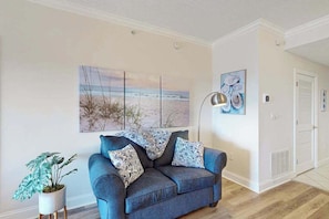 A living room with a sofa, a potted plant, and wall art. - Summer House 202 (Ocean City)