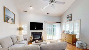 Una sala de estar con sofá, chimenea, televisión y ventilador de techo.
