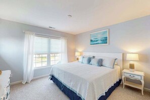 A bedroom with a bed, two bedside tables with lamps, a window with curtains, and a painting on the wall. - River Run 135 (Berlin)