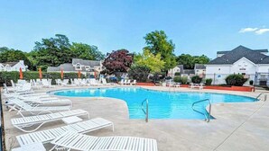 Una piscina con sillones de descanso y una terraza de hormigón.