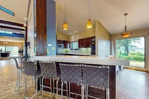 A modern kitchen with a bar area, large windows, and a high ceiling. - Marina Dr 11347 (Berlin)
