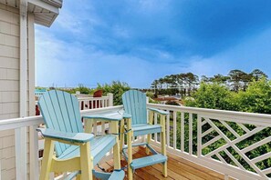 Une terrasse en bois avec deux chaises Adirondack et une rambarde blanche.