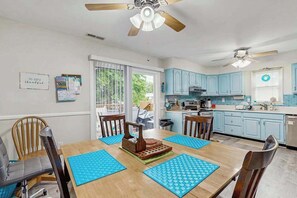 A dining area with a wooden table, blue placemats, and a ceiling fan. - Beach Retreat (Ocean City)