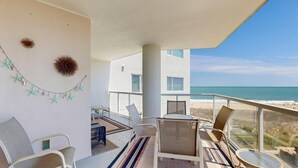 Un balcón con sillas, una mesa y decoración de estrellas de mar en la pared.