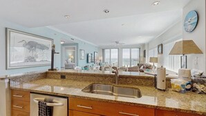 Un amplio salón con cocina, ventanas grandes y vista al océano.